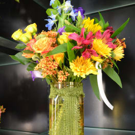Colorful mixed bouquet in a glass vase with yellow, pink, and blue flowers