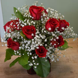 Red roses with baby's breath in a dark vase
