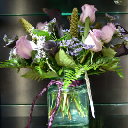 Lavender roses and purple filler flowers in a glass vase