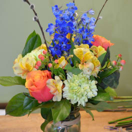 Colorful bouquet in a glass vase with blue flowers and orange roses