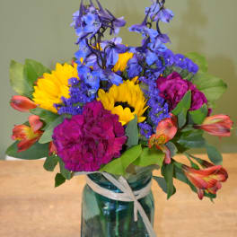 Colorful bouquet in a blue glass jar with a ribbon tie