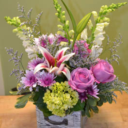 Mixed bouquet with pink roses, lilies, and purple flowers in a wooden box