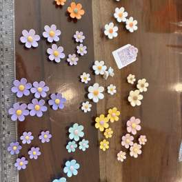 Assorted small pastel daisy decorations arranged on a wooden surface