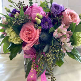 Mixed pink and purple bouquet in a clear glass vase with ribbon