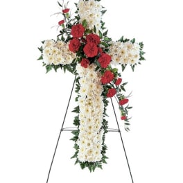 Cross-shaped floral standing spray with white and red flowers on an easel