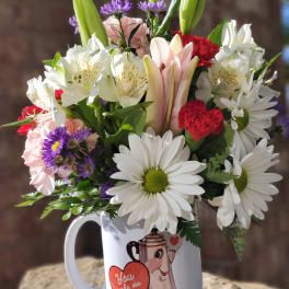 Mixed bouquet of lilies, daisies, carnations, and asters in a white mug