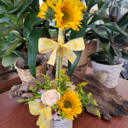 Sunflower and rose arrangement with yellow ribbon in a white container