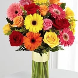 Colorful bouquet of gerbera daisies and roses in a glass vase