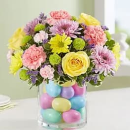 Colorful bouquet in a clear vase filled with pastel eggs