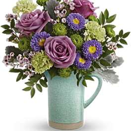 Purple roses and mixed blooms in a mint ceramic pitcher