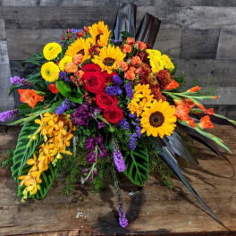 Vibrant horizontal arrangement with sunflowers, red roses, orchids and mixed flowers on a rustic wooden surface