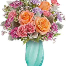 Bouquet of peach and pink roses in a turquoise vase