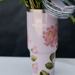 Pink floral Stanley tumbler holding green stems and leaves