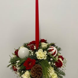 Holiday centerpiece with a red taper candle, roses, and ornaments
