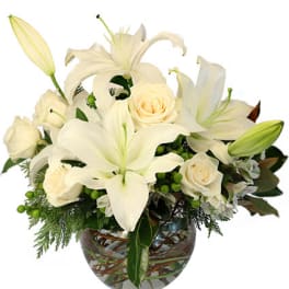 Low arrangement of white lilies and roses in a round glass vase