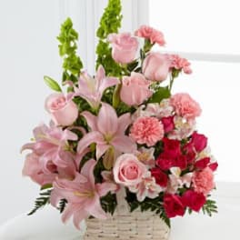 Pink lilies, roses, and carnations in a white basket