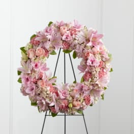 Pink floral wreath on a black stand