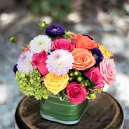 Colorful bouquet of roses and pom-pom flowers in a green vase