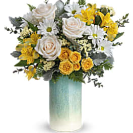 Tall vase of white roses, daisies, and yellow flowers in a blue ombré cylinder