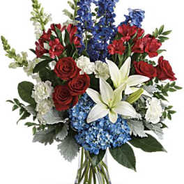 Bouquet of red roses, white lilies, blue flowers, and white snapdragons in a glass vase