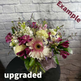 Mixed bouquet with a pink gerbera daisy and purple blooms in a glass vase
