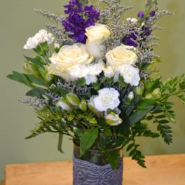 White roses and purple flowers in a glass vase with lace wrap