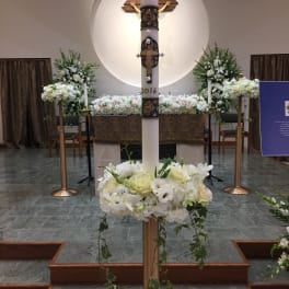 White floral altar arrangements in a church with a central cross