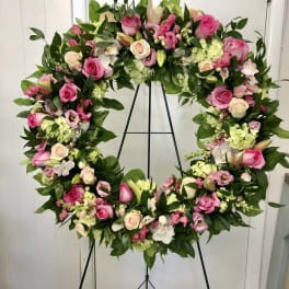 Large pink and white floral wreath on a black stand