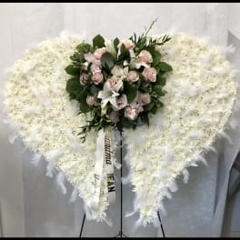 Heart-shaped white funeral spray with pink roses and lilies