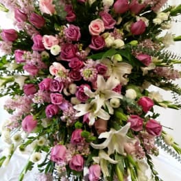 Large standing spray of pink roses, white lilies, and pale filler flowers