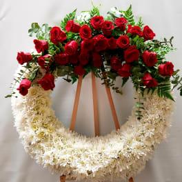 Red roses and white chrysanthemum wreath on a wooden easel