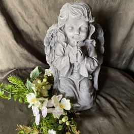 Gray praying angel statue with a small white floral garland