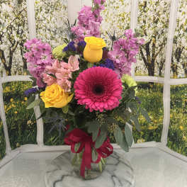 Mixed bouquet in a glass vase with pink, yellow, and purple flowers