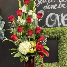 Tall arrangement of red roses and white flowers in a glass vase