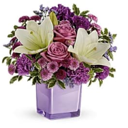 Purple and white floral arrangement in a lavender vase