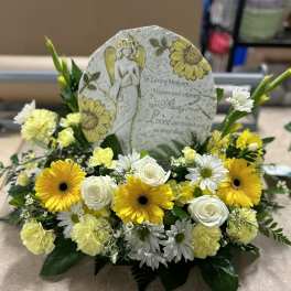 Yellow and white floral sympathy arrangement with an angel memorial plaque