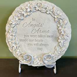 Round memorial plaque with floral relief and an engraved sympathy message