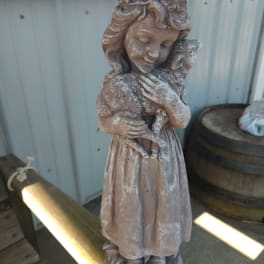 Weathered garden statue of a girl holding a small animal