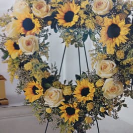 Heart-shaped floral wreath with sunflowers and cream roses on an easel