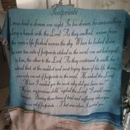 A woven blanket with a beach scene and printed text hangs over a chair