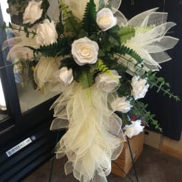 White rose funeral spray with mesh ribbon on a standing easel