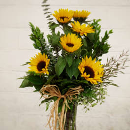 Sunflower arrangement in a glass vase with a raffia bow