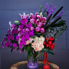 Bouquet of pink lilies, roses, orchids, and hydrangea in a glass vase