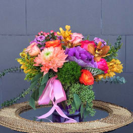Colorful mixed bouquet in a glass vase with a pink ribbon