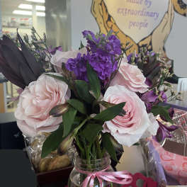 Pink and purple bouquet in a glass jar tied with a pink ribbon