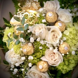 Bouquet of cream roses with gold-wrapped chocolates and white filler flowers