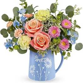 Mixed bouquet in a blue floral pitcher with pink roses and colorful blooms