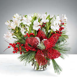 White alstroemeria arrangement in a glass vase with red ribbon and berries