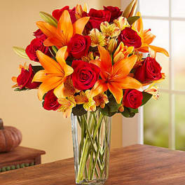 Bouquet of red roses and orange lilies in a clear glass vase