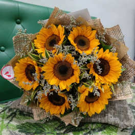Bouquet of sunflowers with small white filler flowers wrapped in burlap
